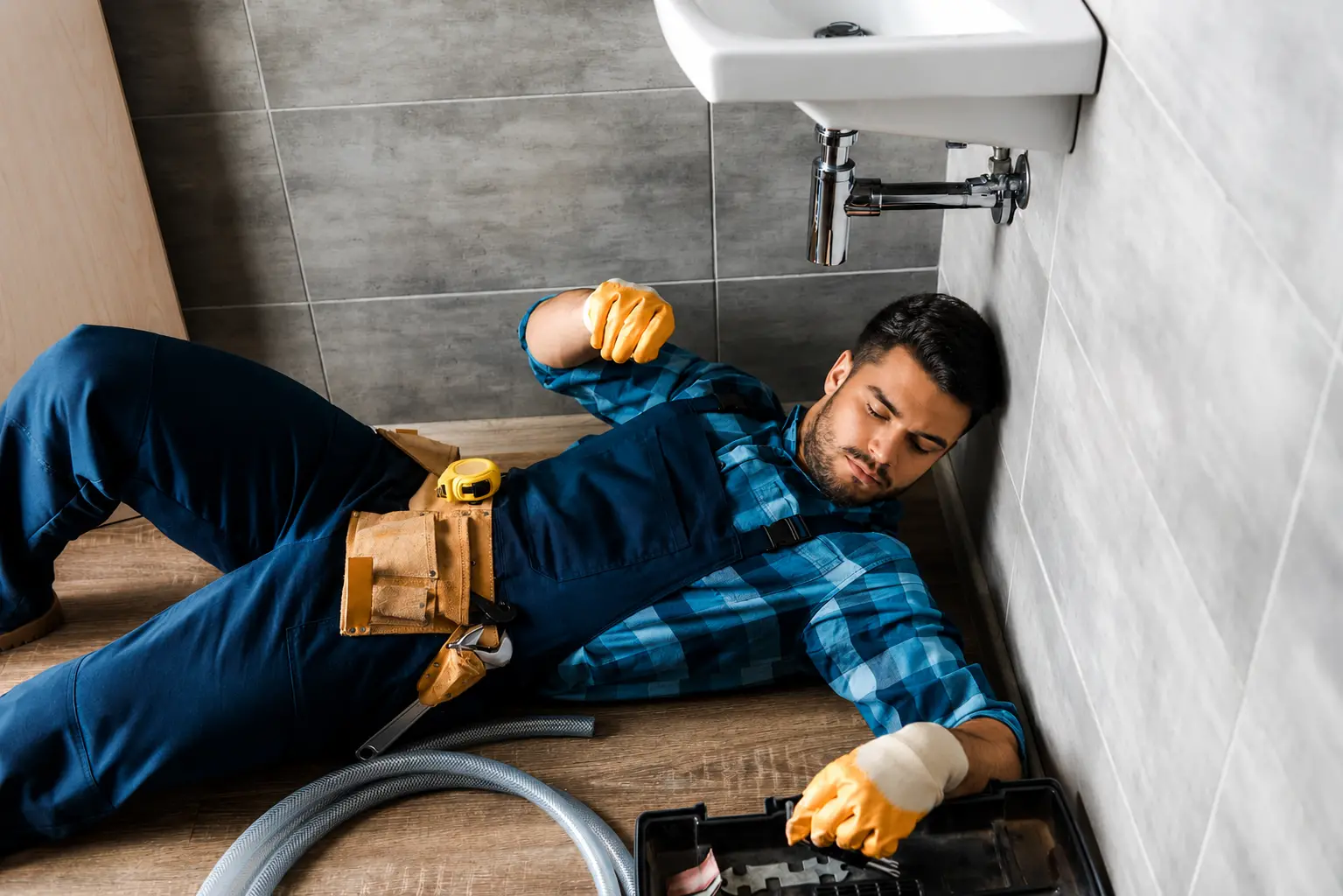 24 hour plumber Bastrop TX inspecting bathroom pipes with toolbox on floor